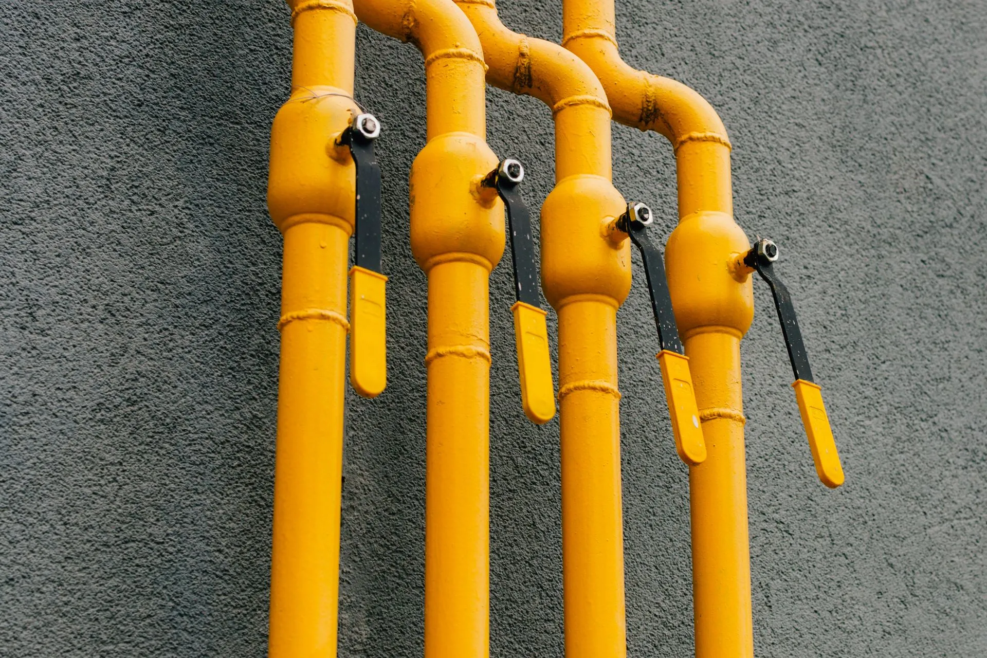 Yellow gas pipe with crane goes along facade new multi-storey building